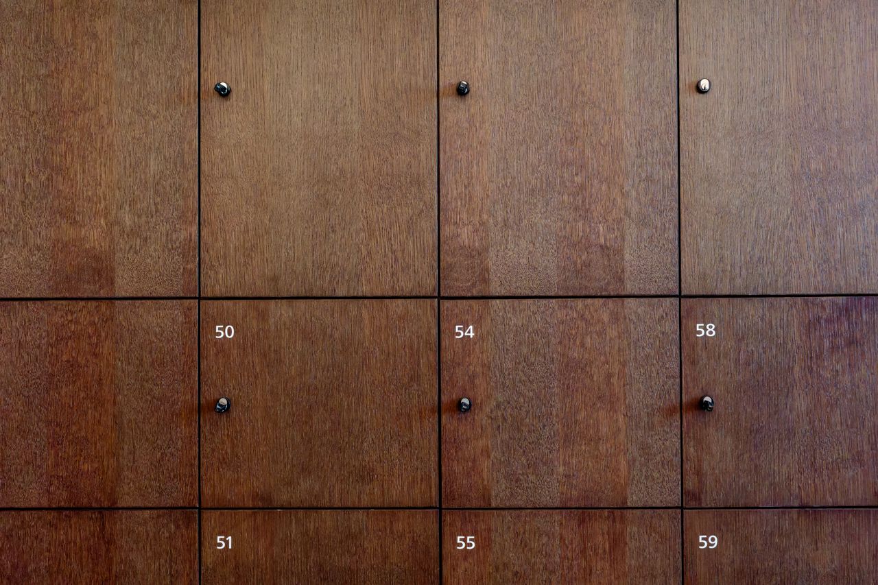 Close-up of wooden locker doors with numbers and knob handles.